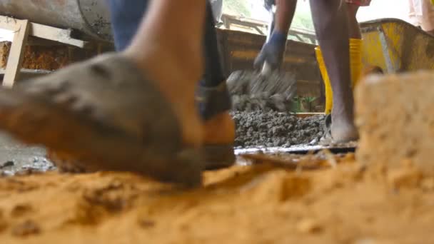 Vista de ángulo bajo de hombres indios irreconocibles paleando manualmente cemento húmedo en la pila en el sitio de construcción. Constructores locales trabajando en el área de construcción. Concepto de proyecto futuro. De cerca. — Vídeos de Stock