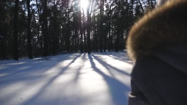 Kamera, beyaz, temiz karla kaplı çayırlarda koşan tanınmayan kızı takip ediyor. Mutlu kadın kışın ve güneşli bir günde özgürlüğün tadını çıkarıyor. Kış tatili kavramı. Yavaş çekim. Yakın çekim. — Stok video