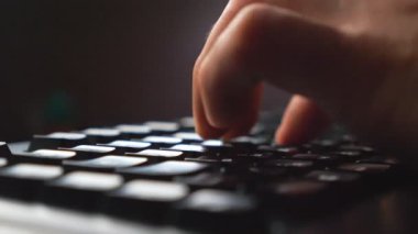 Bilgisayar klavyesinde yazı yazan erkek parmaklarındaki detaylı görünüm. Bilgisayar kullanarak yeni bir proje üzerinde çalışan tanınamayan programcı. Verimli bir gece çalışması. Yavaş çekim. Yakın çekim.