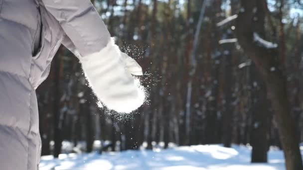 Donna irriconoscibile con guanti bianchi che applaudono e fiocchi di neve che cadono. Ragazza in piedi tra la foresta invernale e giocare con la neve in bella giornata invernale. Sfondo sfocato. Rallentatore Close up — Video Stock