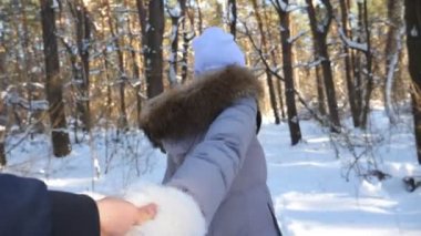 Erkek elini tutan ve karlı ormanda koşan bir kız. Beni takip edin, genç bir kadın kış ormanında erkek arkadaşını çekiyor. Manzaralı kış ortamı. İlişki kavramı. Pov Ağır çekim Yakın çekim