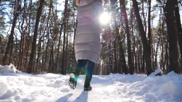 Неузнаваемая женщина бежит по снежному лесу и бросает горсть снега. Веселая девушка наслаждается прекрасным зимним днем. Беззаботная леди с радостными эмоциями на открытом воздухе. Зимняя концепция. Медленное движение — стоковое видео