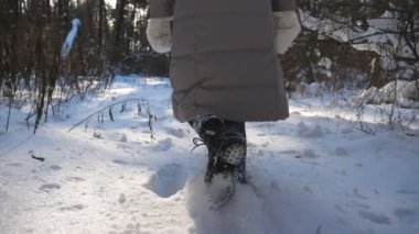 Kışlık giysiler içinde tanınmayan bir kadın karlı ormanda yürürken derin kara basıyor. Soğuk kış gününde yürüyüş yapan kadın yürüyüşçünün bacaklarının arkası. Kız dışarı çıkıyor. Pov Ağır çekim Yakın çekim