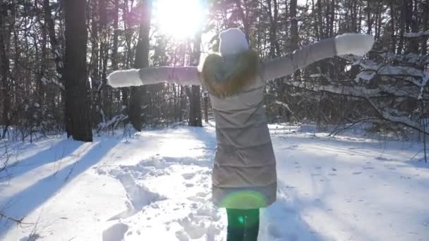 Camera volgen naar onherkenbaar meisje loopt op pad door besneeuwd bos. Gelukkige vrouw genietend van wintertijd en vrijheid op zonnige dag. Begrip wintervakantie. Langzame beweging Close up Achteraanzicht — Stockvideo