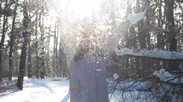 Jonge gelukkige vrouw in winterkleding gooien handvol sneeuw en genieten van vallende sneeuwvlokken. Aantrekkelijk meisje spelen met sneeuw op mooie winterdag. Begrip wintervakantie. Slow mo close-up — Stockvideo
