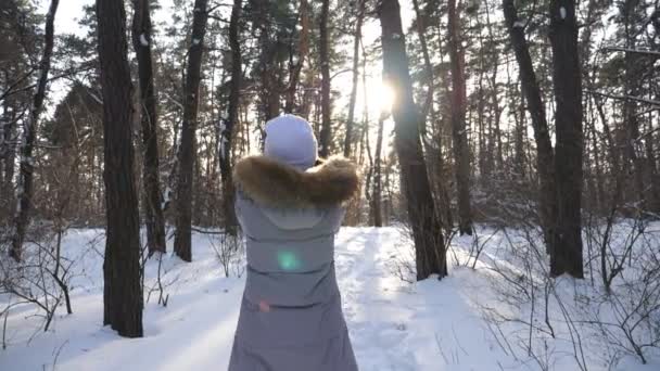 Mulher irreconhecível em roupas de inverno jogando mão cheia de neve. Menina desfrutando de inverno e liberdade no dia ensolarado de inverno. Luz solar brilhante brilhando através de flocos de neve caindo no fundo. Movimento lento — Vídeo de Stock