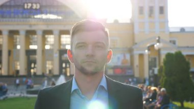 Arka planda şehir manzarasıyla şehir caddesinde yürüyen kendine güvenen iş adamının portresi. Yakışıklı bir adam şehirde gezinirken etrafa bakıyor. Dışarı çıkan başarılı adamın yüzü. Yavaş çekim. Yakın çekim.
