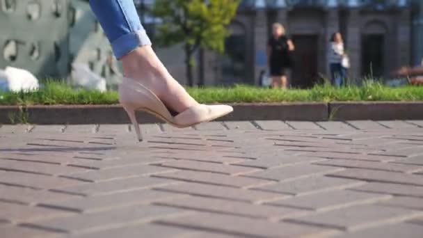 Female legs in high heels shoes walking through urban street. Feet of young woman in high-heeled footwear going in city. Unrecognizable girl stepping at sidewalk. Side view Slow motion Close up — Stock Video