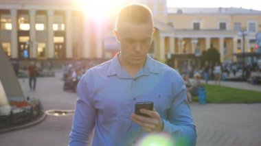 Zengin iş adamı şehir ortamında akıllı telefon kullanıyor ve neşeli başarılar elde ediyor. Başarılı bir adam iş hayatında ya da başarılı bir anlaşmada şansı kutluyor. Neşeli duyguları olan bir adamın portresi. Yavaş çekim