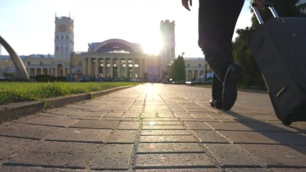 Wealthy businessman walking at urban street with his luggage. Confident man going to terminal with beautiful cityscape and sunset at background. Successful guy being on his way to flight. Slow motion — Stockvideo