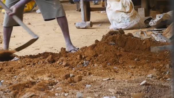 Weinig zicht op mannelijke indiaanse handen harkt zand of grond met een schoffel op de bouwplaats. Lokale onherkenbare bouwer werkt op de bouwplaats. Concept van toekomstig project. Sluiten Slow motion — Stockvideo