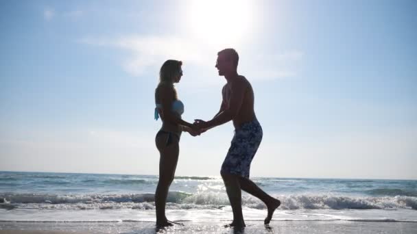 Genç adam dizlerinin üzerinde duruyor ve kız arkadaşına yaz tatilinde evlenme teklif ediyor. Deniz kıyısında mutlu bir çift kucaklaşma ve öpüşme. Deniz manzaralı yeni evlilere bir bakın. Aşk ve mutluluk kavramı — Stok video