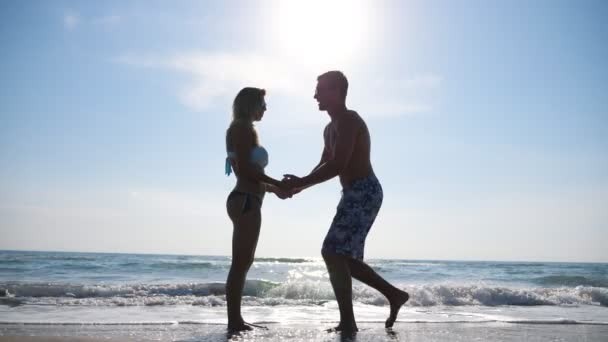 Hombre joven de pie en la rodilla y la propuesta de matrimonio a su novia vacaciones de verano. Feliz pareja abrazándose y besándose en la orilla del mar. Vista de los recién casados en el fondo del paisaje marino. Concepto de amor y felicidad — Vídeo de stock