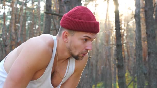 Retrato del corredor cansado tomando un descanso después del entrenamiento de carrera dura en el bosque. Tipo atlético descansando después de entrenar limpiando el sudor de su cara. Hombre haciendo ejercicios de cardio al aire libre. Concepto de estilo de vida activo — Vídeos de Stock