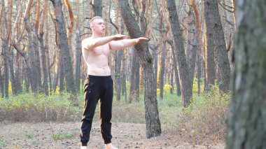 Güzel ormanda çömelme hareketleri yapan sporcu bir adam. Genç sporcu dışarıda egzersiz yapıyor. Doğada atlet eğitimi. Sağlıklı ve aktif yaşam tarzı kavramı. Dolly vuruldu. Yaklaş..