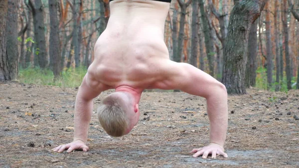 年轻的肌肉男在森林里把手倒立 硬汉和强壮的家伙在做特技表演在木材 在室外展示体操锻炼的运动员的近身身体 活泼和健康的生活方式 — 图库照片
