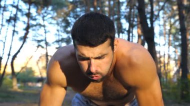 Ormanda sıkı çalıştıktan sonra mola veren yorgun adamın portresi. Sporcu, antrenmandan sonra yüzündeki teri sildikten sonra dinleniyor. Sıcak yaz gününde kardiyo egzersizi yapan bir adam. Yavaş çekim. Yakın çekim.