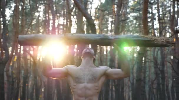 肌肉男子举重超过头部训练的手。强壮的人赤身裸体在森林里锻炼运动员在美丽的自然环境中运动。运动和积极的生活方式。Dolly shot — 图库视频影像