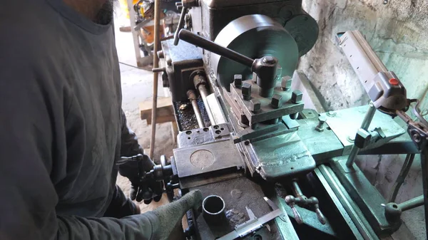 Unrecognizable man working with old workbench in his garage or workshop. Mechanic using lathe for metal processing. View on turning work. Slow motion Close up.