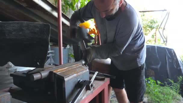 Volwassen man die met metaal werkt. Smid verwerking van ijzer detail met behulp van hamer. Monteur of monteur die buiten werkt. Langzame beweging Dolly shot — Stockvideo