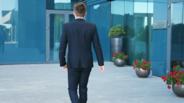 Joven hombre de negocios irreconocible caminando por la ciudad. Empresario viajando al trabajo en el entorno urbano. El tipo de confianza en traje está de camino al edificio de oficinas. Vista trasera trasera en cámara lenta — Vídeos de Stock