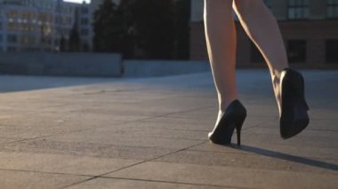 Yüksek topuklu ayakkabılı kadın bacakları şehir caddesinde yürüyor. Şehirdeki yüksek topuklu ayakkabılı genç iş kadınının ayakları. İşe giden bir kız. Yavaş çekim. Yakın çekim.
