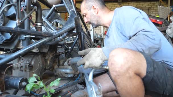 Volwassen monteur repareert voertuig. Aandachtig reparateur vaststelling van auto. Auto master doet zijn werk in garage of werkplaats. Een man die auto 's repareert. Langzame beweging Close-up — Stockvideo