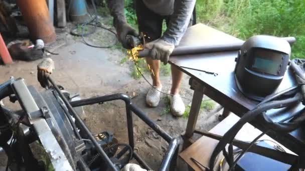 Mecánico irreconocible moliendo metal en su lugar de trabajo. Trabajador cortando algún detalle usando sierra circular. Vista en el escritorio de reparador y chispas volando alrededor. Hombre aserrando parte de hierro. Dolly disparó — Vídeos de Stock