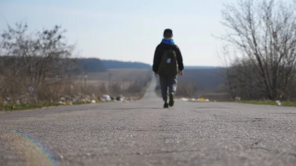 バックパックを持つ認識できない小さな男の子の訓練への道の間を歩く ジャケットを着た男性の子供は学校へのドライブウェイに沿って行きます キャップの小さな子供は晴れた日に移動します 燃えるような動き クレーンショット — ストック写真