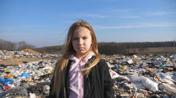 아이의 더러운 쓰레기 처리장의 배경에 비추어 카메라를 들여다보고 시골의 쓰레기장에 — 스톡 사진