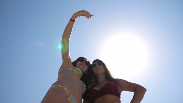Χαρούμενη ελκυστική μελαχρινές λήψη selfie πορτρέτο στο smartphone. Νεαρές ανέμελες γυναίκες φωτογραφίζουν κατά τη διάρκεια των καλοκαιρινών διακοπών. Ευτυχισμένες κυρίες με γυαλιά ηλίου που ποζάρουν στην κάμερα. Κοπέλες αναπαύονται μαζί. — Αρχείο Βίντεο