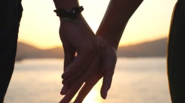 Gün batımında kadın ve erkek el ele tutuşuyorlar. Genç bir çift deniz kıyısında duruyor ve birlikte vakit geçirmekten zevk alıyor. İki sevgili arasındaki romantik an. Sevgi ya da mutluluk kavramı. Yavaş çekim