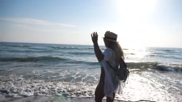 Mujer feliz en traje de baño corriendo al mar mostrando emociones alegres. Chica bronceada joven disfrutando de la libertad y las vacaciones de verano largamente esperadas en la orilla del mar. Hermoso paisaje marino en el fondo. Movimiento lento — Vídeos de Stock