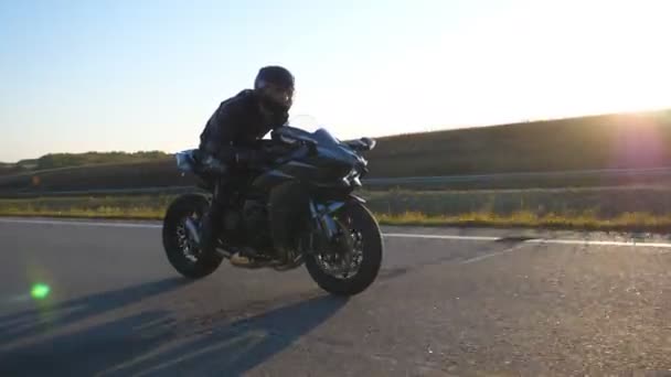 Uomo che guida su moto sportive moderne in autostrada con bagliore di sole sullo sfondo. Motociclista corse la sua moto su strada di campagna. Un tizio che guida la bici durante il viaggio. Concetto di libertà. — Video Stock