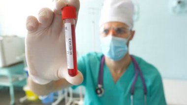 Bilim adamları Coronavirus 'a kan örneği veren bir test tüpü tutuyor. Koruyucu eldivenleri olan bir laboratuar çalışanı kan örneklerini klinikte test ediyor. COVID-19 salgınından sağlık ve güvenlik hayatı kavramı