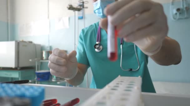 Científico analiza muestras de sangre a COVID-19 y añade tubo de ensayo en el estante en el laboratorio. Examen médico probeta con muestra de sangre a coronavirus. Concepto de vida de salud y seguridad de la pandemia del virus de la corona — Vídeo de stock