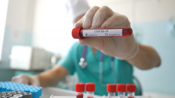 Cientista segurando tubo de teste com amostra de sangue para coronavírus. Braço de trabalhador de laboratório com luvas de proteção testando amostras de sangue na clínica. Conceito de vida em saúde e segurança da pandemia de COVID-19 — Vídeo de Stock