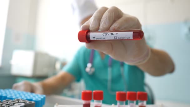 Wetenschapper houdt reageerbuis met bloedmonster aan coronavirus. Arm van laboratoriummedewerker met beschermende handschoenen die bloedmonsters op de kliniek testen. Concept van gezondheid en veiligheid door COVID-19 pandemie — Stockvideo