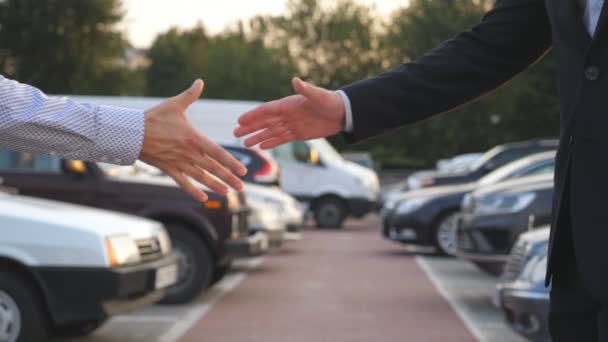 Manos masculinas en traje dando llaves de coche a su amigo. El brazo del hombre de negocios pasa la llave del coche. Saludo entre dos hombres de negocios al aire libre. Primer plano: cámara lenta — Vídeo de stock