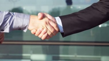Ofis binası yakınlarında başarılı bir anlaşma yaptıktan sonra kendine güvenen iki işadamı el sıkışıyor. Şehir ortamında birbirlerini tebrik eden genç meslektaşlar. İş ortaklarının el sıkışması. Yavaş çekim