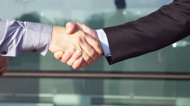 Two confident businessmen shaking hands after successful deal near office building. Young colleagues congratulating each other in urban environment. Handshake of business partners. Slow motion — Stock Video