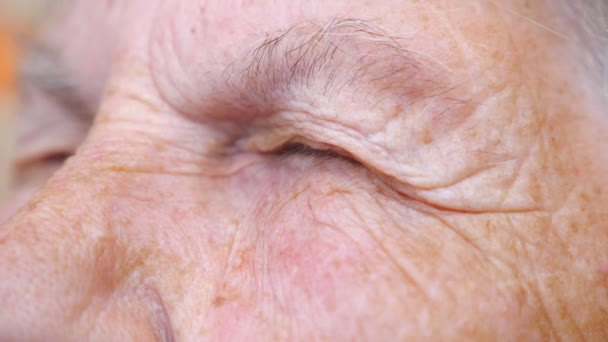 Detail view on closed eyes of old woman. Close up of wrinkled female face. Granny opening her eyes and looking to something showing surprise emotions. Granny with calm facial expression. Slow motion — Stock Video