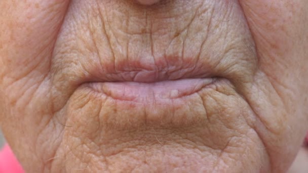 Nahaufnahme der Lippen der reifen Großmutter. Mund der älteren Oma schickt Luftkuss in die Kamera. Seniorin mit faltiger Haut macht Kuss-Geste. Zeitlupe — Stockvideo