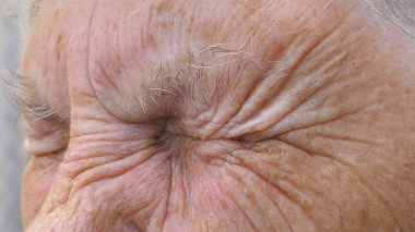 Büyük büyükannenin portresi hüzünlü bir manzarayla uzaktan görünüyor. Yaşlı büyükannemin yakın çekimleri onun gri gözlerini fena bozuyor. Olgun bir kadının kederli yüz ifadesi. Yavaş çekim.