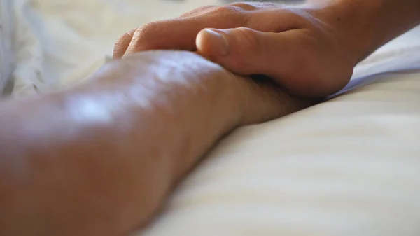 Torunu Yaşlı Büyükannesinin Elini Klinikte Tutuyor Rahatlatıyor Genç Adam Yatakta — Stok fotoğraf