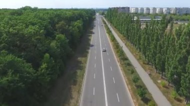 Şehir yolu boyunca beyaz, üstü açık bir arabanın hava manzarası. Cabriolet 'le seyahat eden genç bir çift. Mutlu evli çift birlikte gezinin tadını çıkarıyor. Güneşli bir günde otoyolda araba kullanmak.