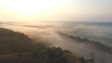 Güneşin doğuşunda sisle kaplı güzel, sonsuz çayır görüntüsü. Sabahın erken saatlerinde sisli kırsal alanda inanılmaz manzara. Güneş ışığı büyük sisli vadi. Harika doğa sahnesi
