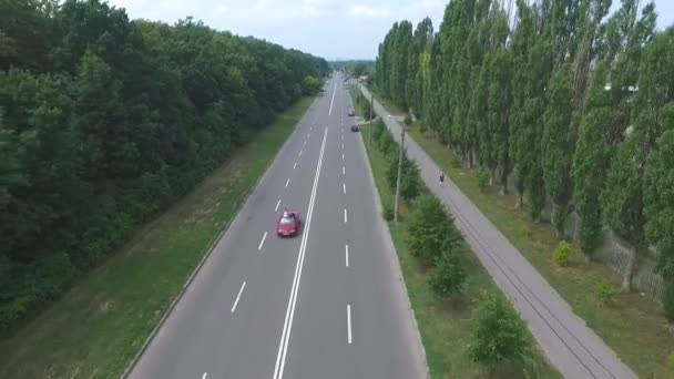 Aerial shot of red convertible car riding through empty highway. Young couple traveling at cabriolet. Happy just married pair enjoying journey. Flying over auto driving at road on summer day. Slow mo — Stock Video