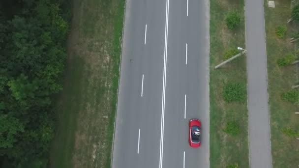 Tiro aéreo de carro conversível vermelho cavalgando pela estrada rural. Casal jovem viajando em Cabriolet. Feliz casal apenas aproveitando a viagem. A sobrevoar a auto-estrada. Conceito de viagem — Vídeo de Stock