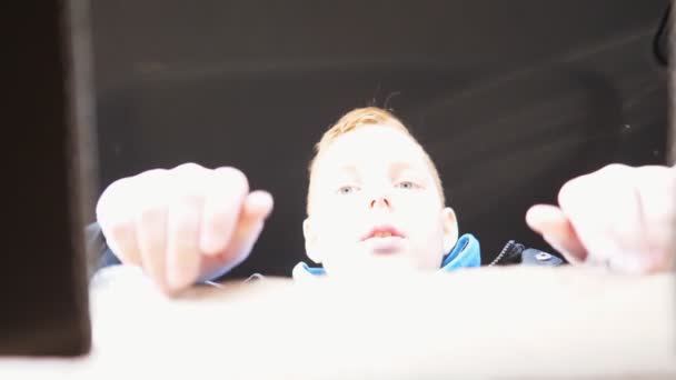 Glückliche kleine rothaarige Junge öffnet Pappschachtel und zeigt Überraschung und Freude auf seinem Gesicht sitzt in einem Auto. Kleines männliches Kind blickt mit positiven Emotionen in die Verpackung. Zeitlupe — Stockvideo